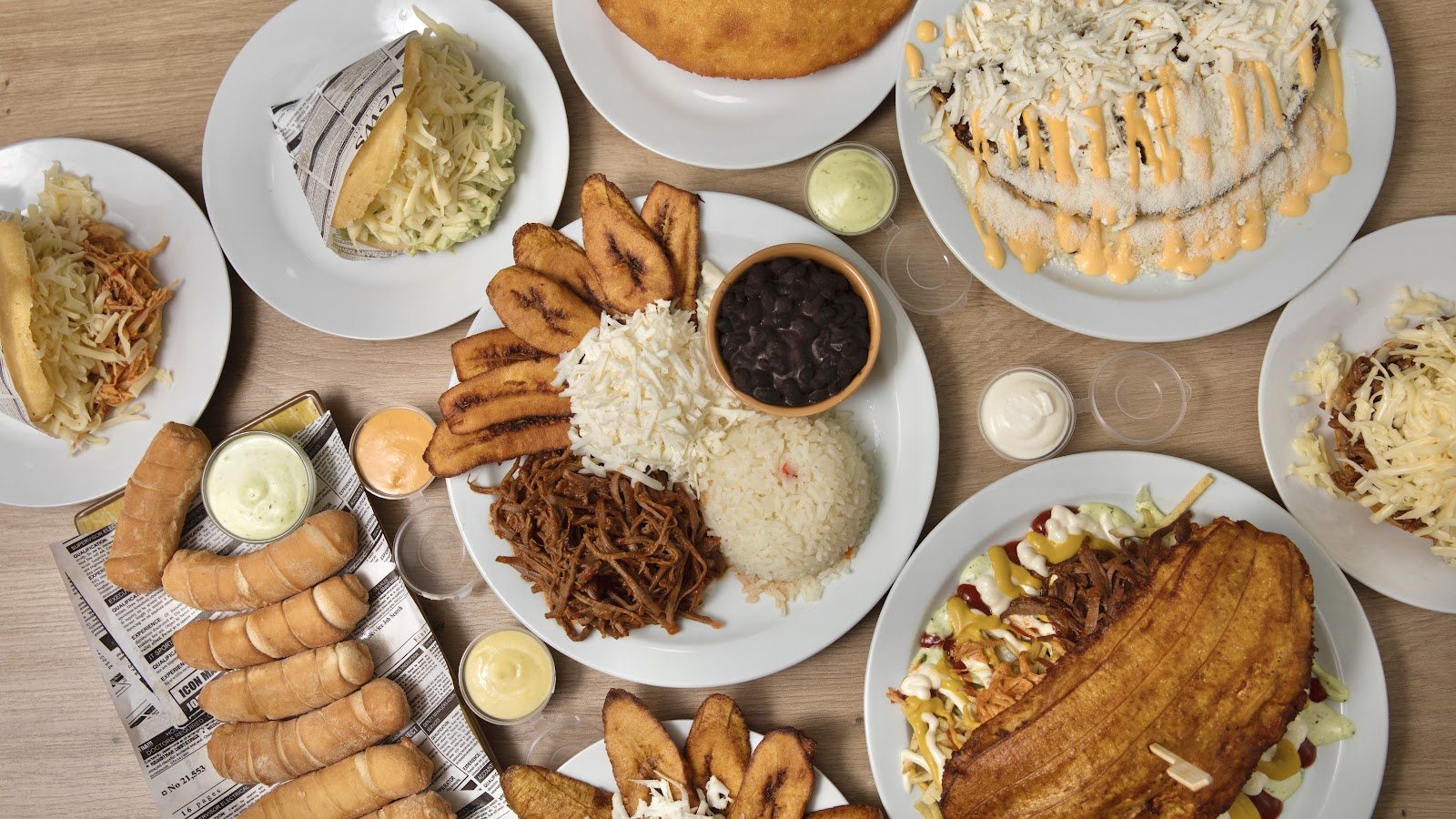 Tabla variada para compartir con tequeños, arepas, plátanos maduros y carne mechada.